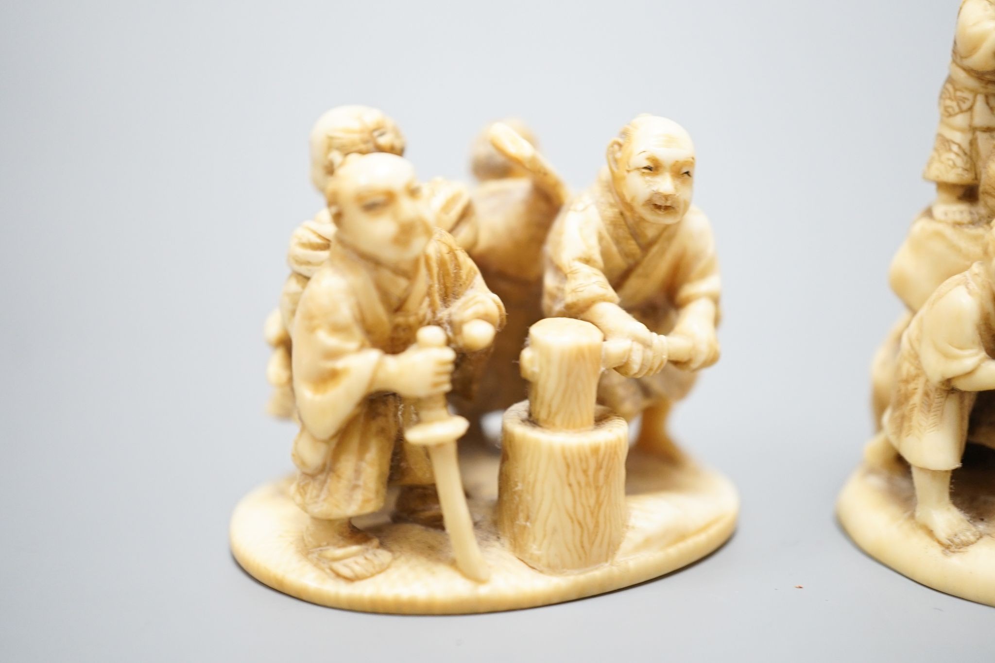 Two Japanese ivory okimono-netsuke of Buddha and attendants and a group of artisans, Meiji period, both signed, tallest 7cm